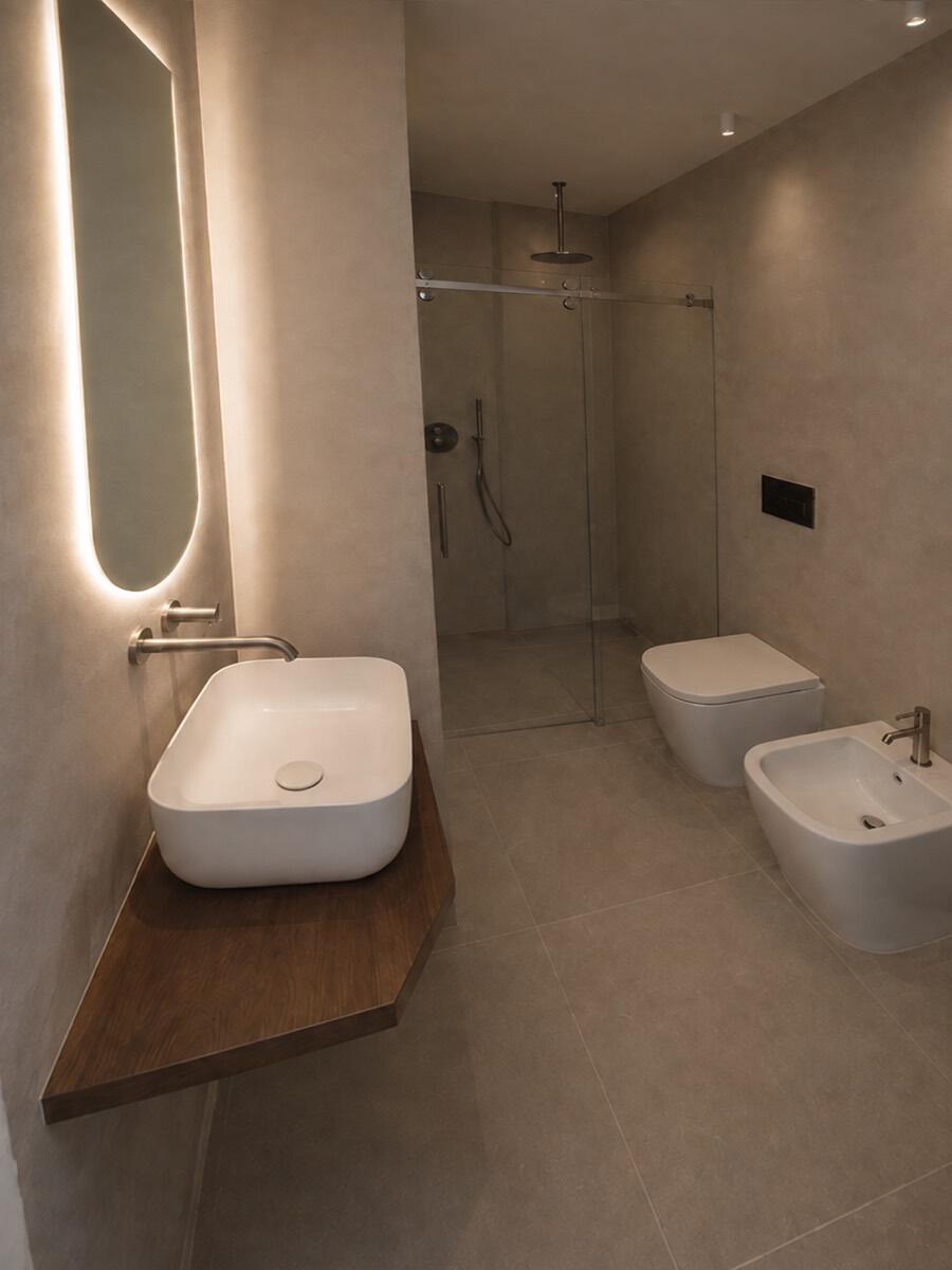 Bagno: lavabo su mensola in rovere, specchio retroilluminato e doccia a pavimento