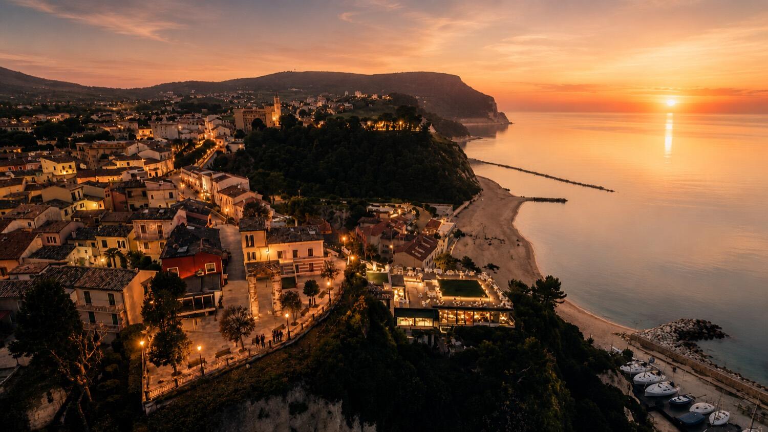 Numana dall'alto al tramonto, il paese sopra la spiaggia e il porto